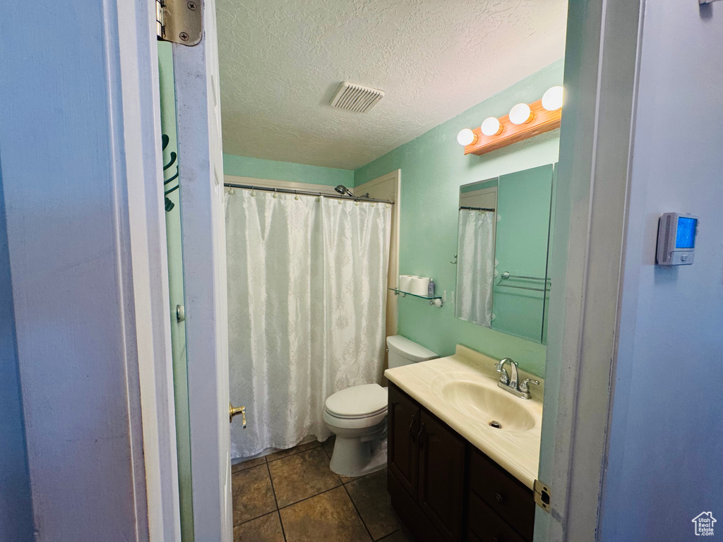 Bathroom featuring vanity, a textured ceiling, tile patterned floors, and a shower with shower curtain