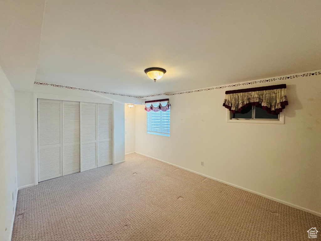 Unfurnished bedroom with light carpet and a closet