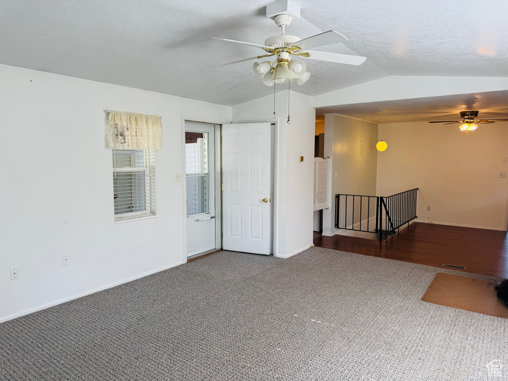 Carpeted spare room with ceiling fan and vaulted ceiling