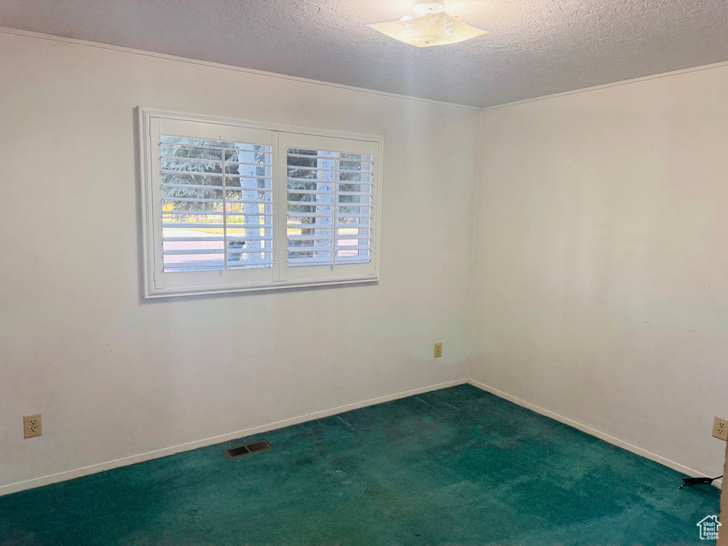 Unfurnished room featuring a textured ceiling, dark carpet, and ceiling fan