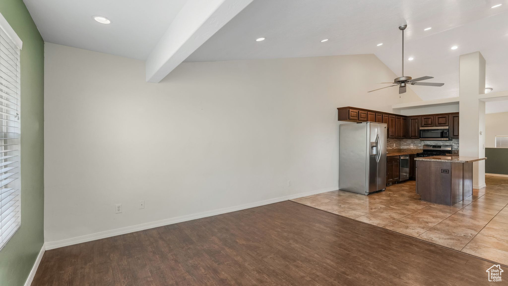 Kitchen featuring appliances with stainless steel finishes, a ceiling fan, light wood finished floors, tasteful backsplash, and plenty of natural light