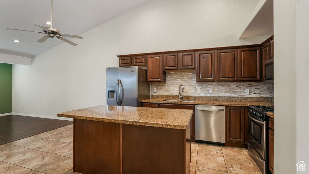 Kitchen featuring appliances with stainless steel finishes, tasteful backsplash, ceiling fan, a kitchen island, and recessed lighting