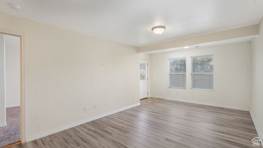 Empty room with light wood-style floors and a smoke detector