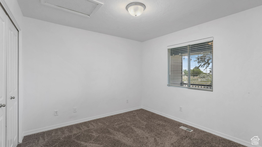 Carpeted empty room featuring attic access and baseboards