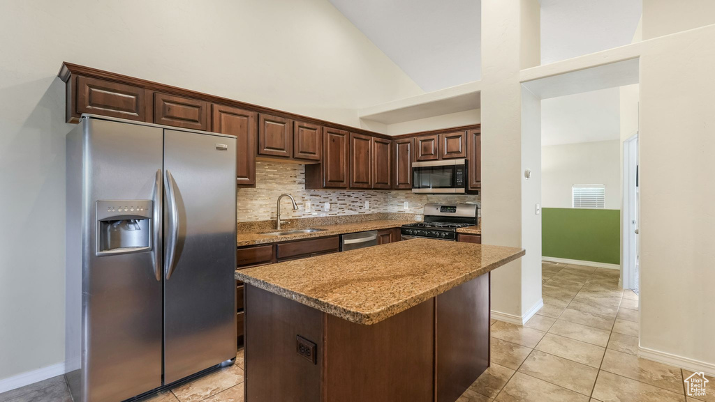 Kitchen featuring stainless steel appliances, decorative backsplash, a center island, dark brown cabinetry, and light tile patterned floors