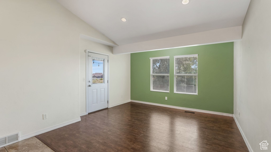 Empty room with vaulted ceiling and wood finished floors