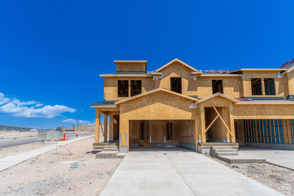 Property under construction featuring driveway and covered porch