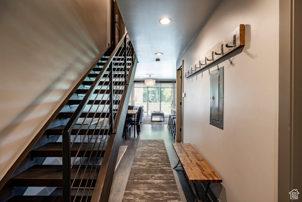 Staircase with electric panel, wood finished floors, and recessed lighting