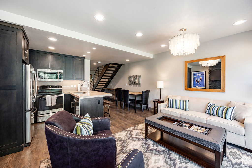 Living area with stairway, recessed lighting, dark wood finished floors, and a chandelier