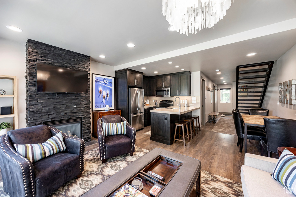 Living area with wood finished floors, a fireplace, a chandelier, and recessed lighting