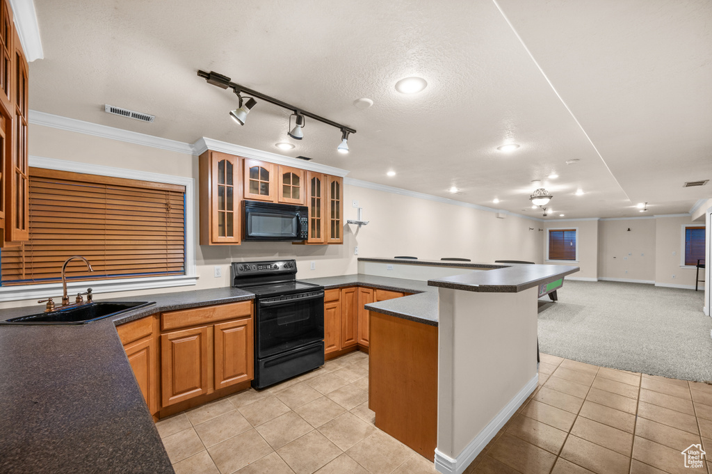 Kitchen with black appliances, a peninsula, light tile patterned floors, dark countertops, and glass insert cabinets