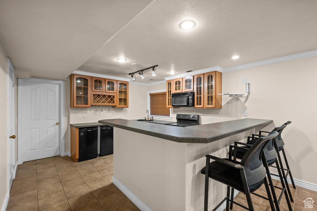 Kitchen featuring black appliances, a peninsula, a textured ceiling, a kitchen breakfast bar, and ornamental molding