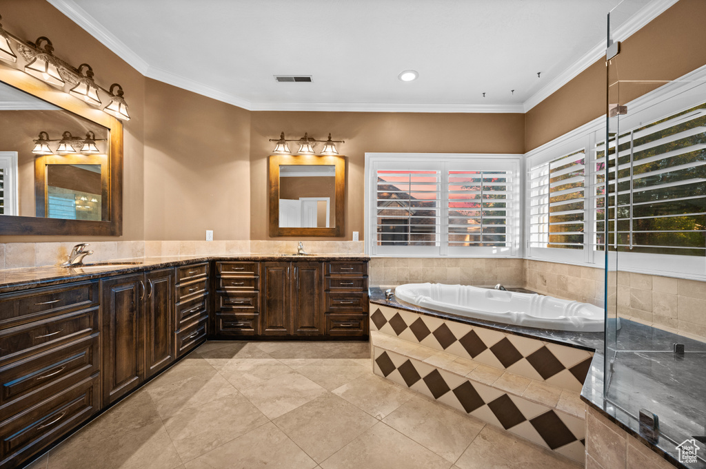 Full bath with double vanity, a garden tub, tile patterned floors, crown molding, and recessed lighting