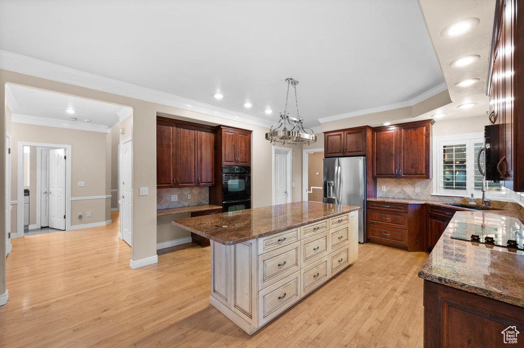Kitchen with stainless steel fridge with ice dispenser, a center island, decorative backsplash, dark stone countertops, and recessed lighting