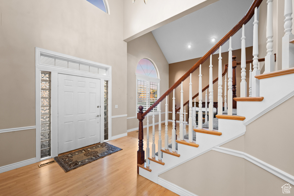Foyer featuring a high ceiling, wood finished floors, stairway, and recessed lighting