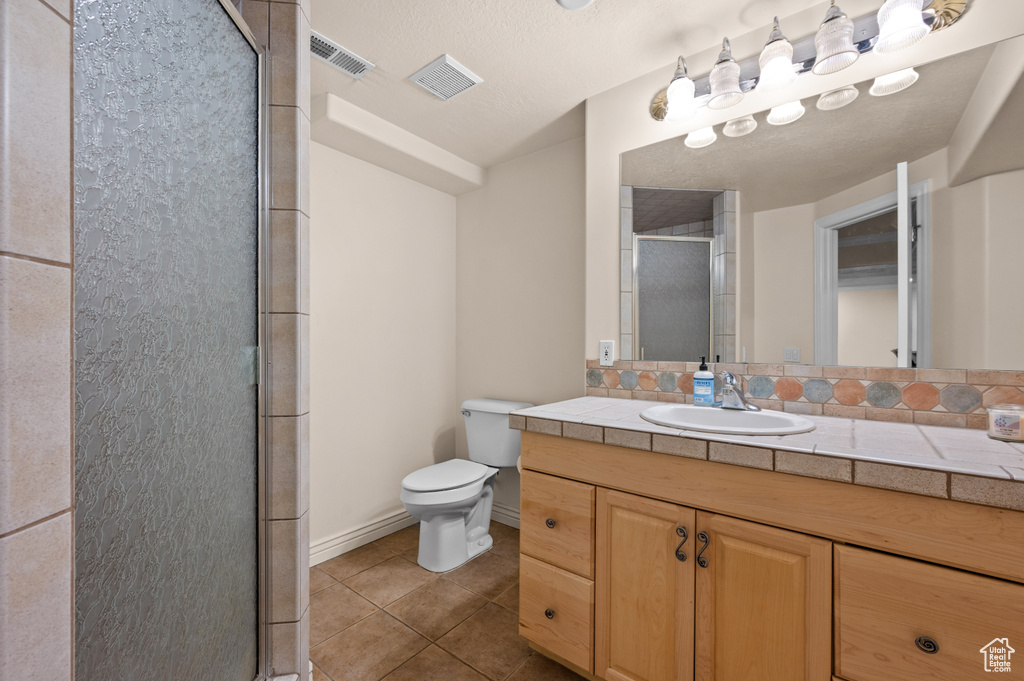 Bathroom with a stall shower, tile patterned flooring, and vanity