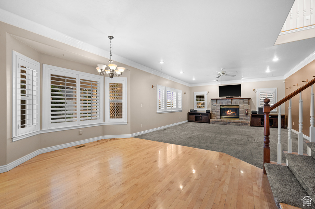 Unfurnished living room featuring a fireplace, wood finished floors, stairway, a ceiling fan, and ornamental molding