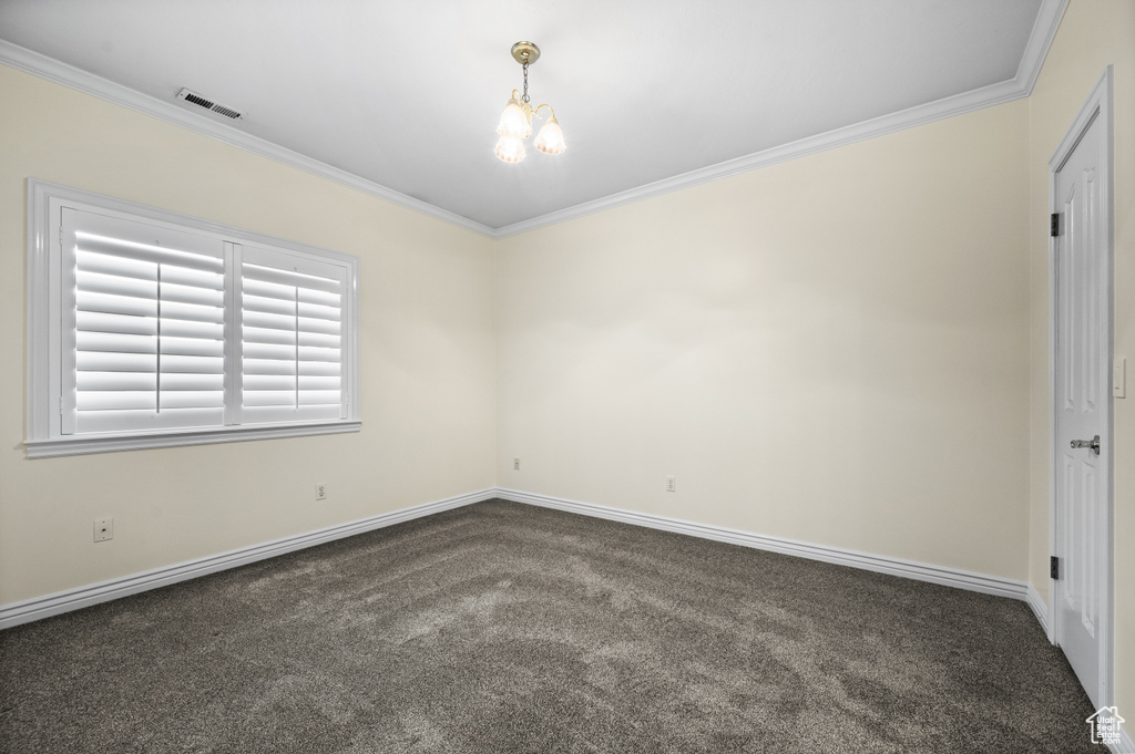 Carpeted spare room with crown molding and a chandelier