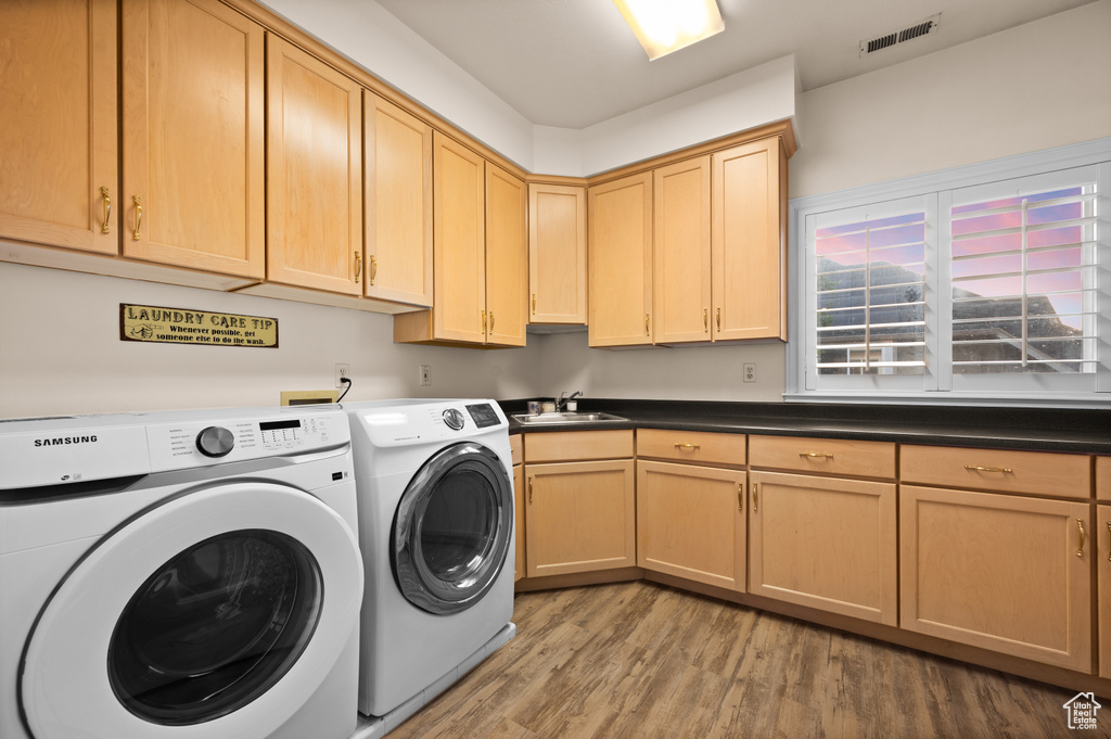 Laundry area featuring washer and clothes dryer, light wood-style flooring, and cabinet space
