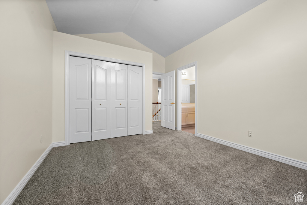 Unfurnished bedroom featuring carpet, lofted ceiling, a closet, and ensuite bath