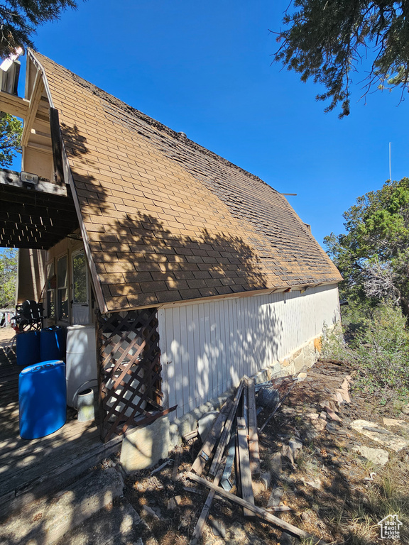 View of side of home with a shingled roof
