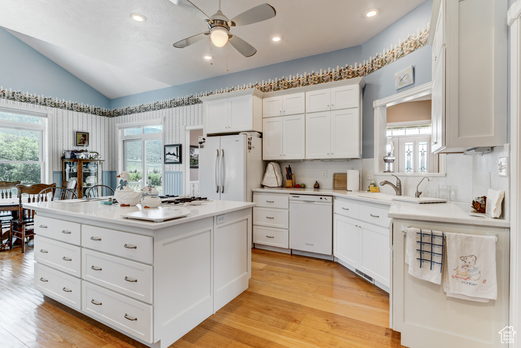 Kitchen featuring white appliances, a ceiling fan, vaulted ceiling, plenty of natural light, and light countertops
