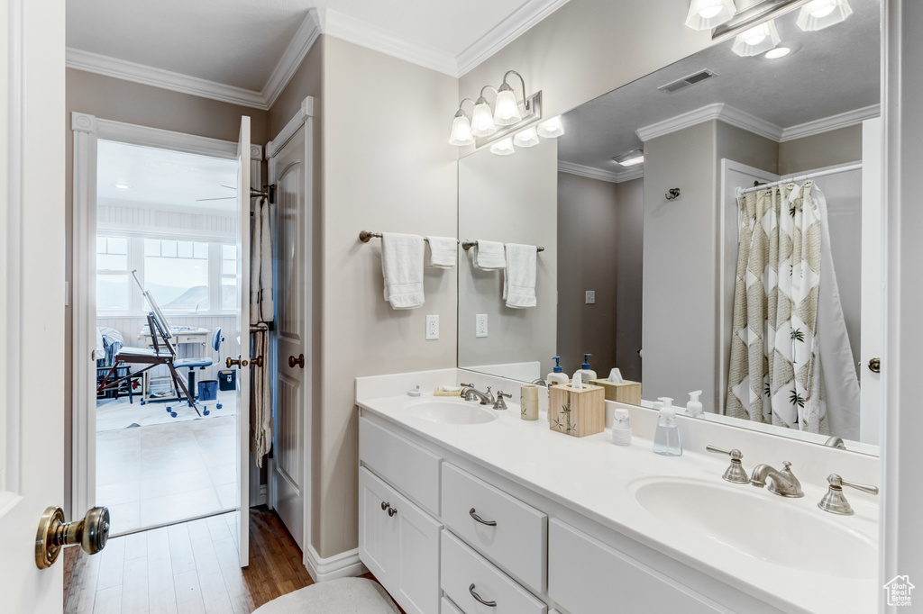 Full bath with double vanity, wood finished floors, ornamental molding, and curtained shower