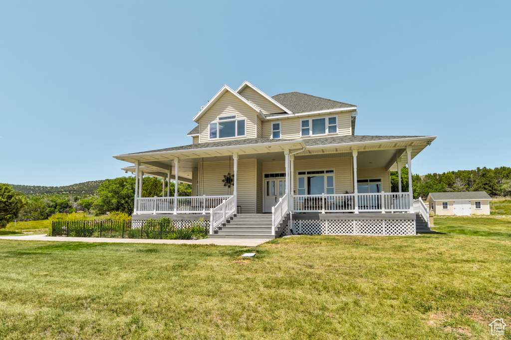 Farmhouse inspired home with covered porch, a front yard, and a shingled roof