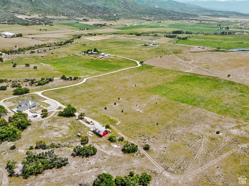 Aerial view of property and surrounding area featuring rural landscape and a mountainous background
