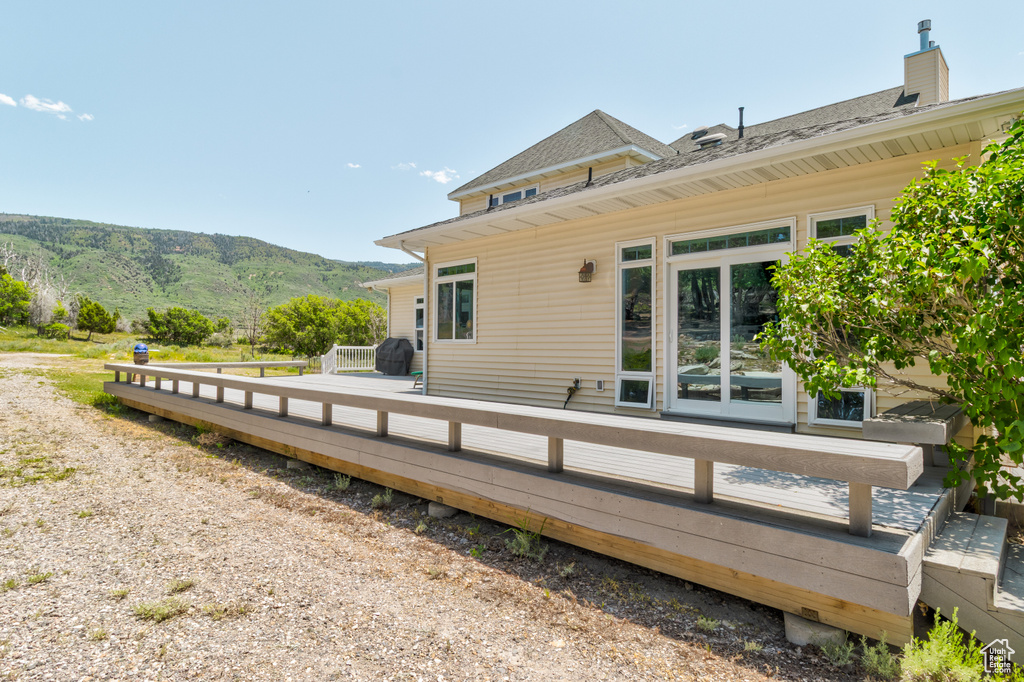 Back of property with a deck with mountain view and a shingled roof