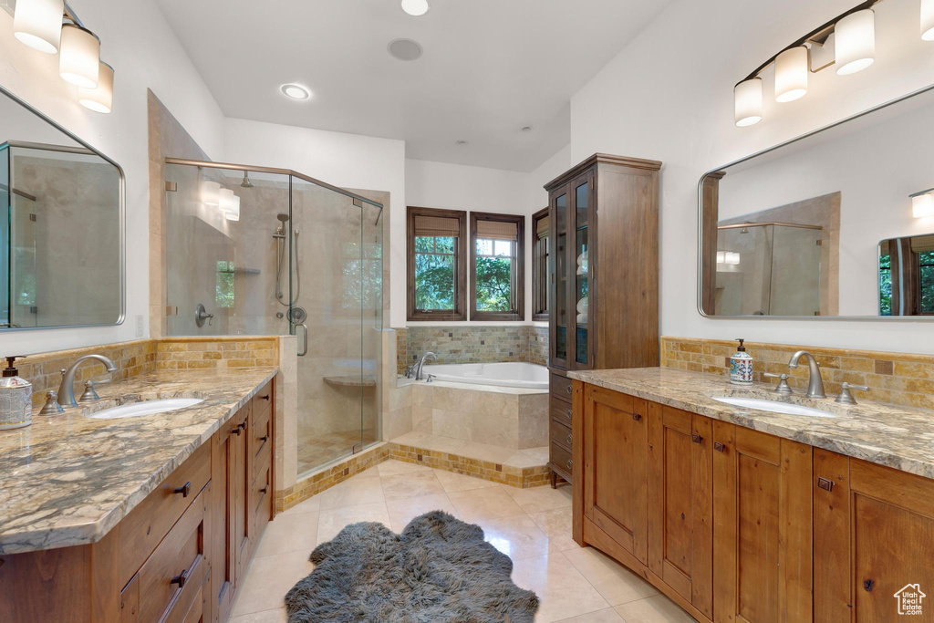 Full bath with two vanities, a shower stall, a garden tub, and tile patterned flooring