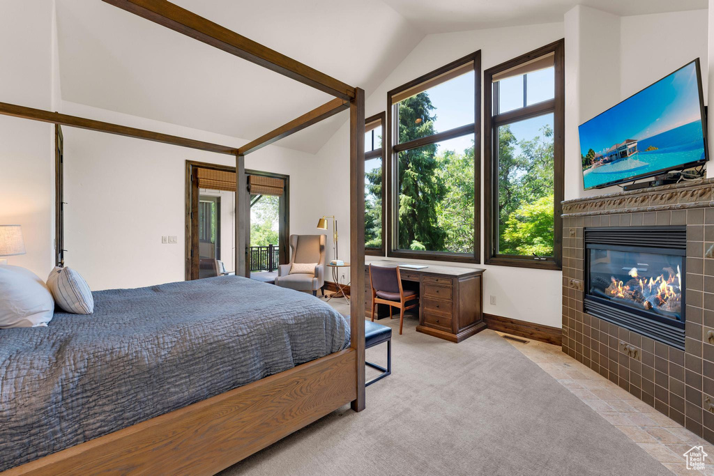 Carpeted bedroom with lofted ceiling and a tiled fireplace