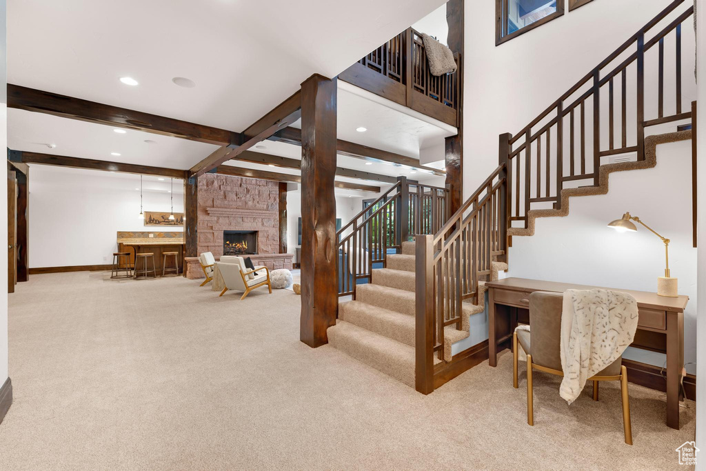 Stairway with carpet, beam ceiling, recessed lighting, and a stone fireplace