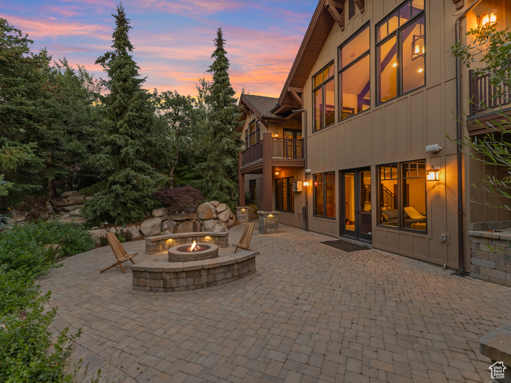 Patio terrace at dusk with a fire pit, a balcony, and a patio area