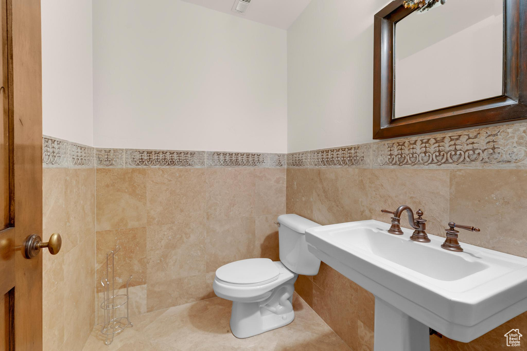 Half bathroom featuring tile walls and wainscoting