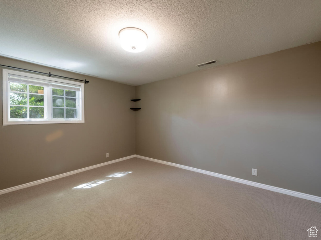 Carpeted spare room featuring a textured ceiling