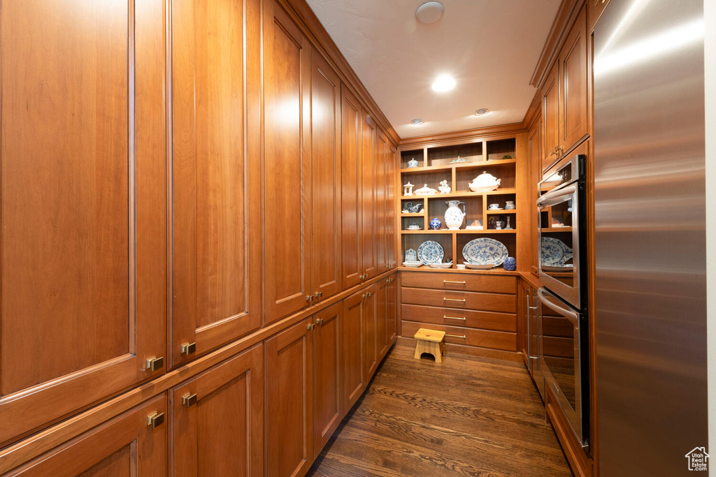 Detailed view of high end refrigerator, stainless steel double oven, and wood finished floors