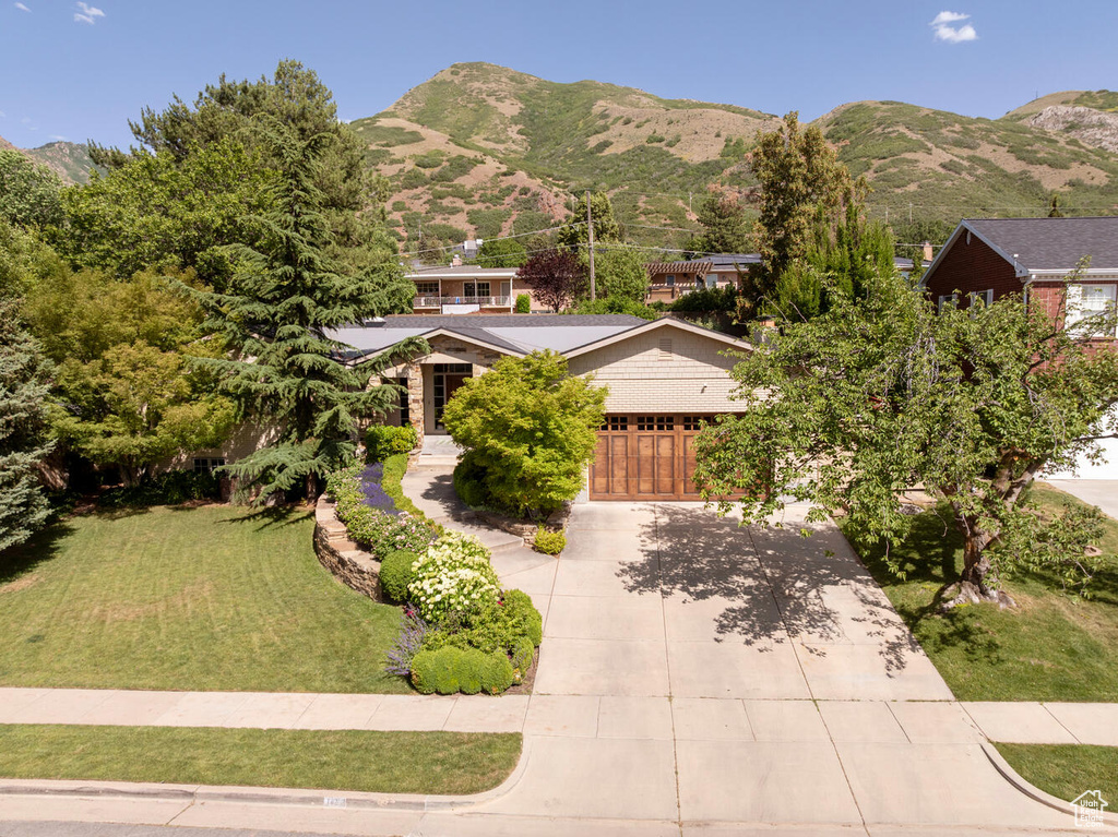 View of front facade with concrete driveway, a garage, a front yard, and a mountain view