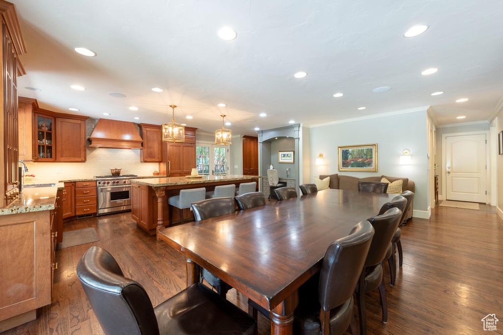 Dining space with crown molding, dark wood-style flooring, recessed lighting, and a chandelier