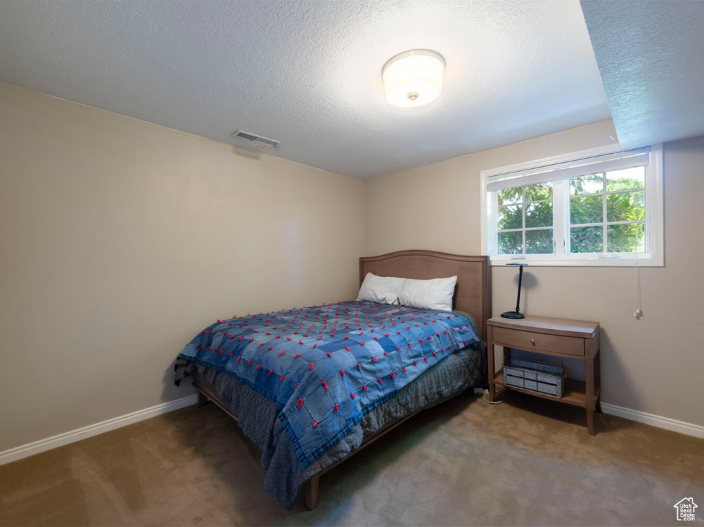 Carpeted bedroom with baseboards and a textured ceiling