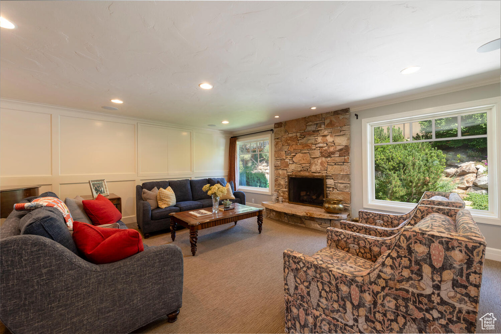 Carpeted living area with healthy amount of natural light, a decorative wall, a fireplace, crown molding, and recessed lighting