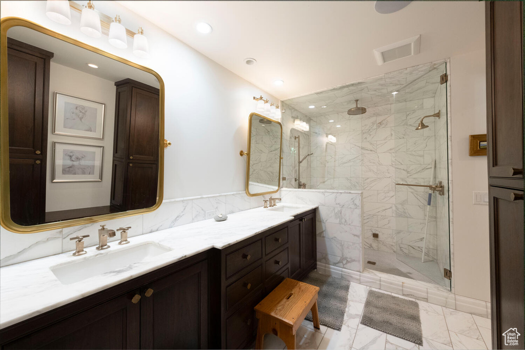 Full bathroom featuring marble finish flooring, a marble finish shower, double vanity, and recessed lighting