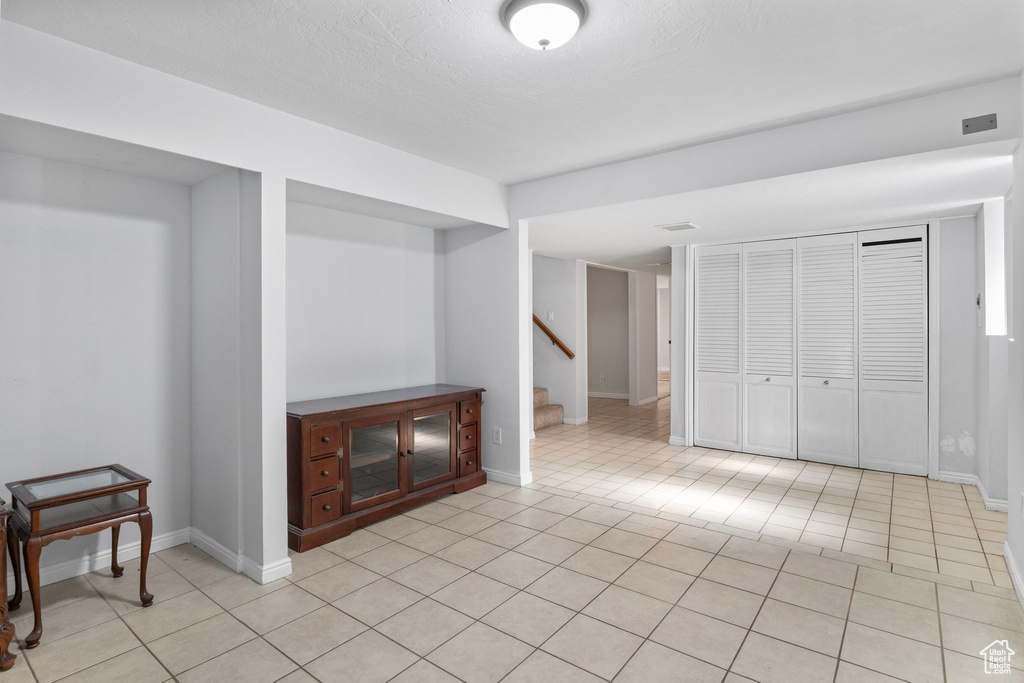 Unfurnished living room with stairs and light tile patterned floors