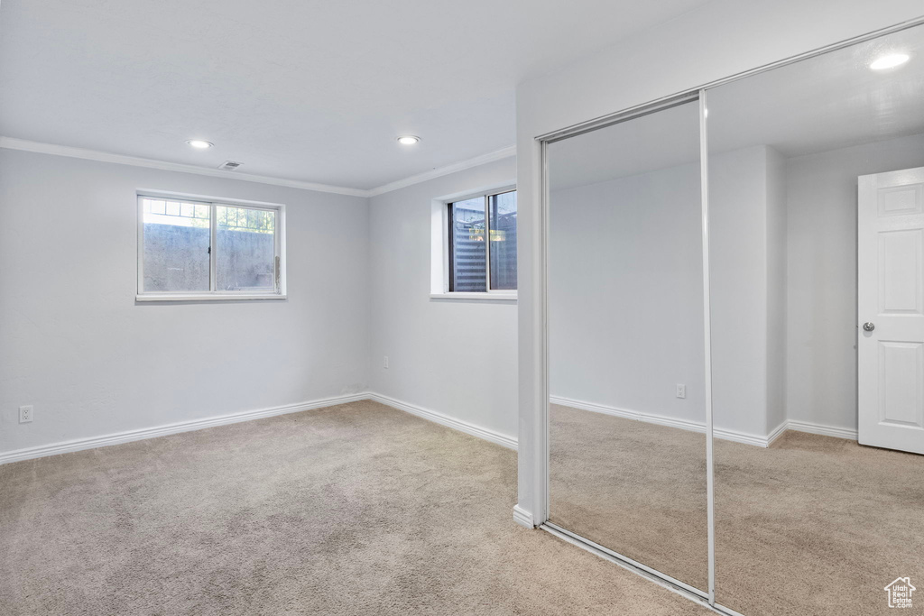 Unfurnished bedroom featuring a closet, carpet floors, crown molding, and recessed lighting
