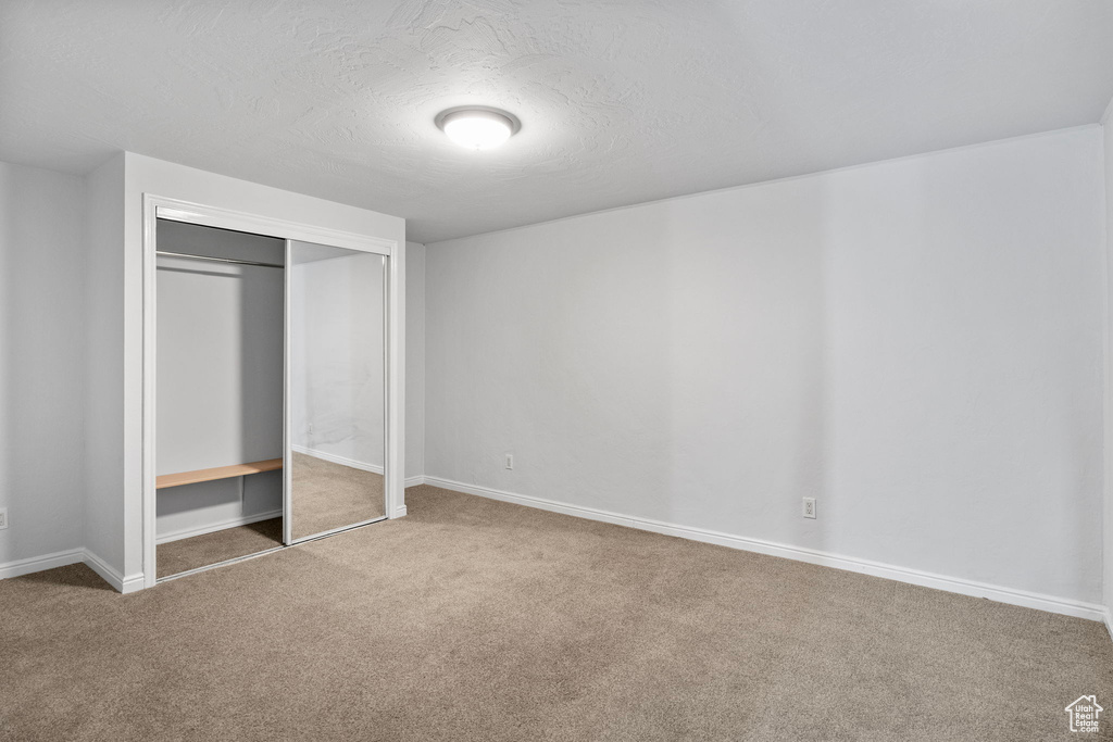 Unfurnished bedroom featuring carpet flooring, a closet, and a textured ceiling