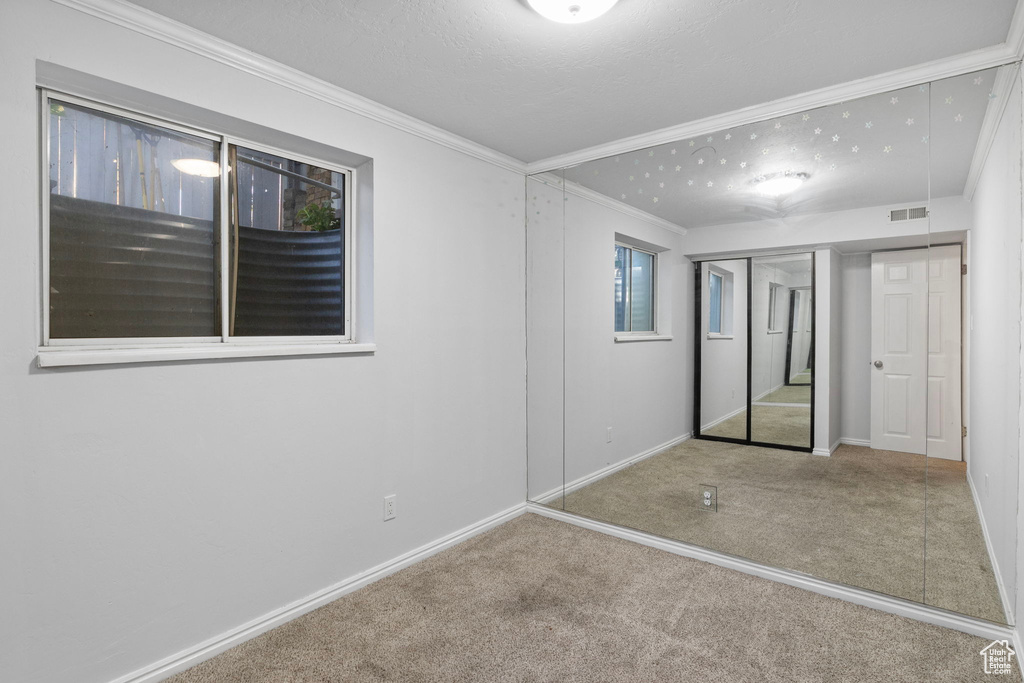 Unfurnished bedroom featuring carpet floors, crown molding, and a closet
