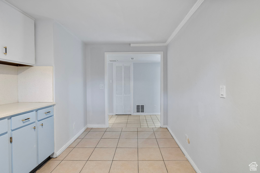 Kitchen featuring light countertops, light tile patterned floors, and crown molding