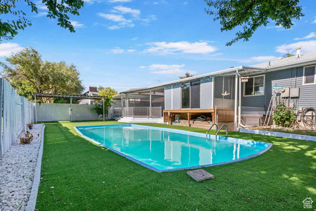 View of swimming pool with a sunroom and a fenced backyard