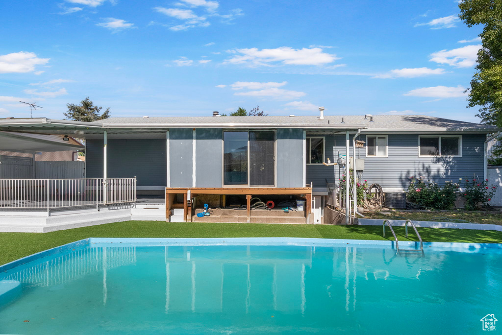 Rear view of property with an outdoor pool, a yard, and a patio