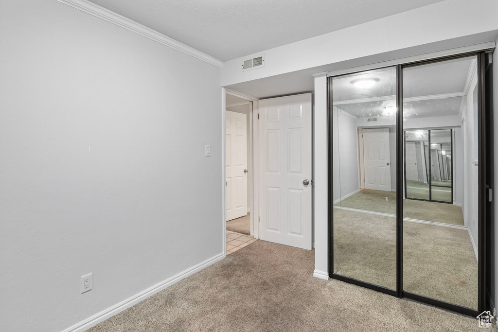 Unfurnished bedroom with carpet, a closet, and crown molding